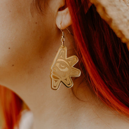 A closeup of a model wearing the "Balance Sun" earring in gold mirror acrylic from Copper Canoe Woman.