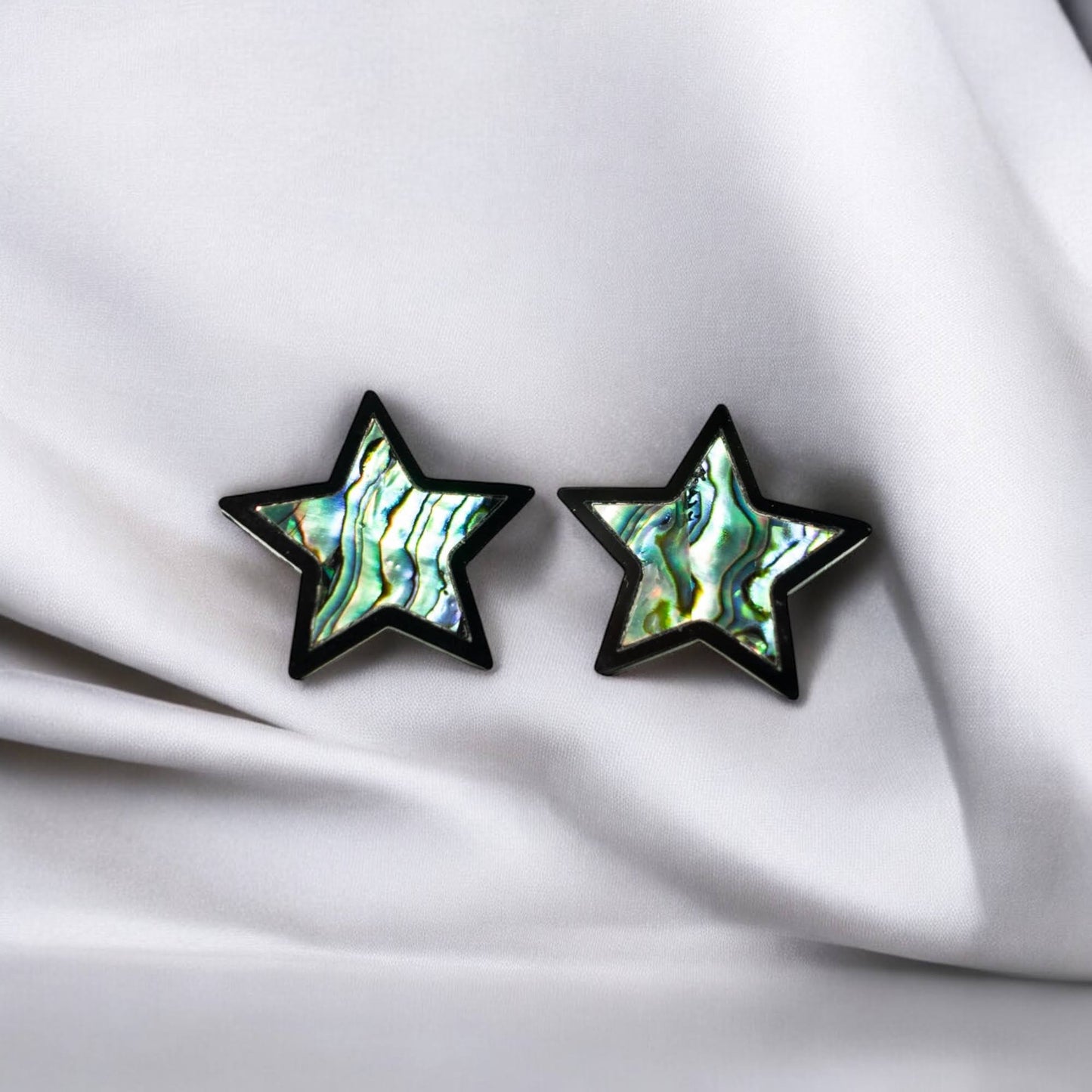 Closeup of a pair of "Bright Star" earrings from Copper Canoe Woman in black acrylic with abalone inlay.