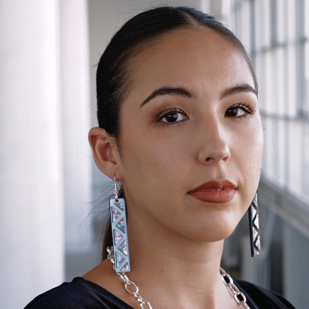 woman wearing charcoal mirror long rectangle warrior spirit earring with triangle zig zag abalone inlay from copper canoe woman