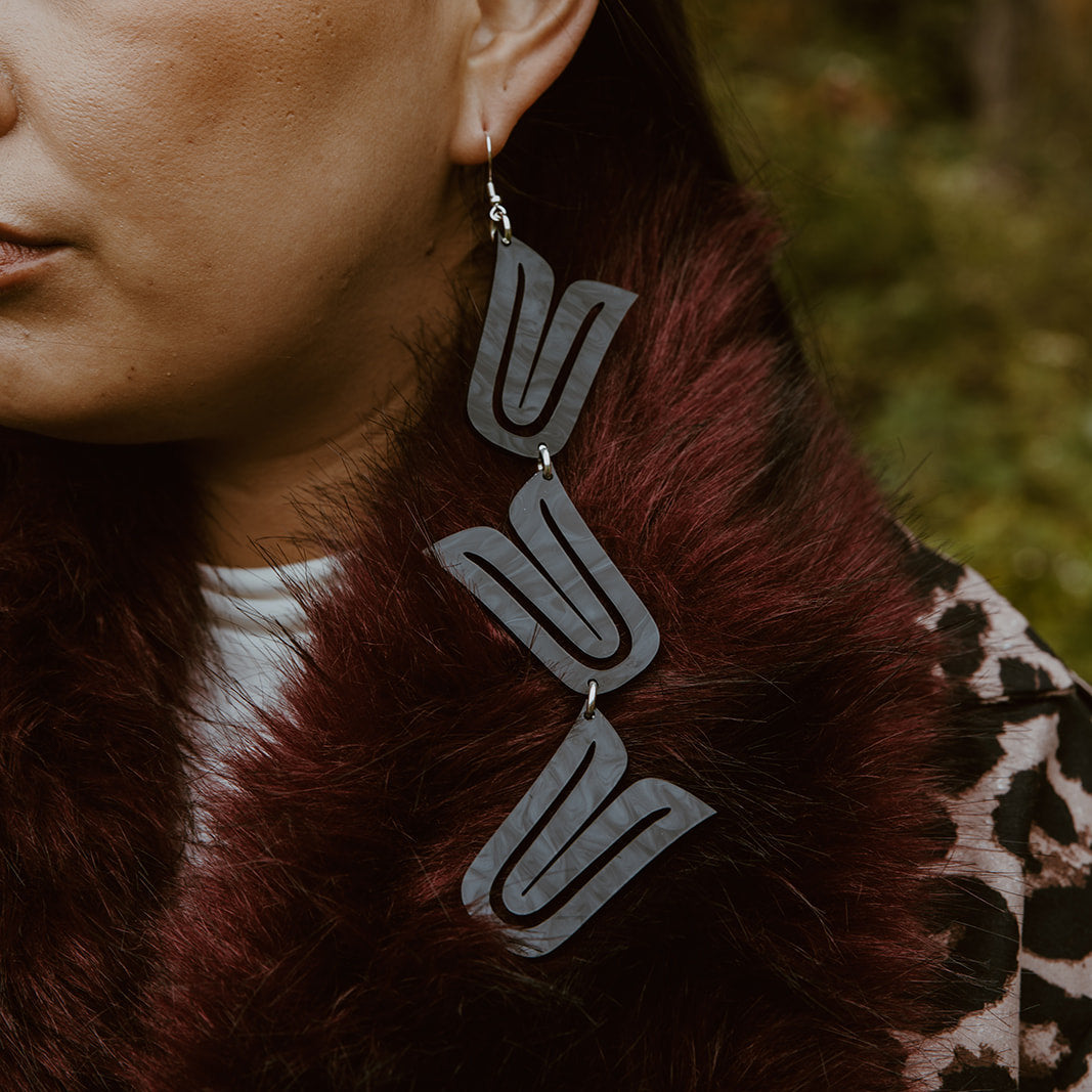 Closeup of model wearing black acrylic "Formline Cascade" earrings from Copper Canoe Woman.