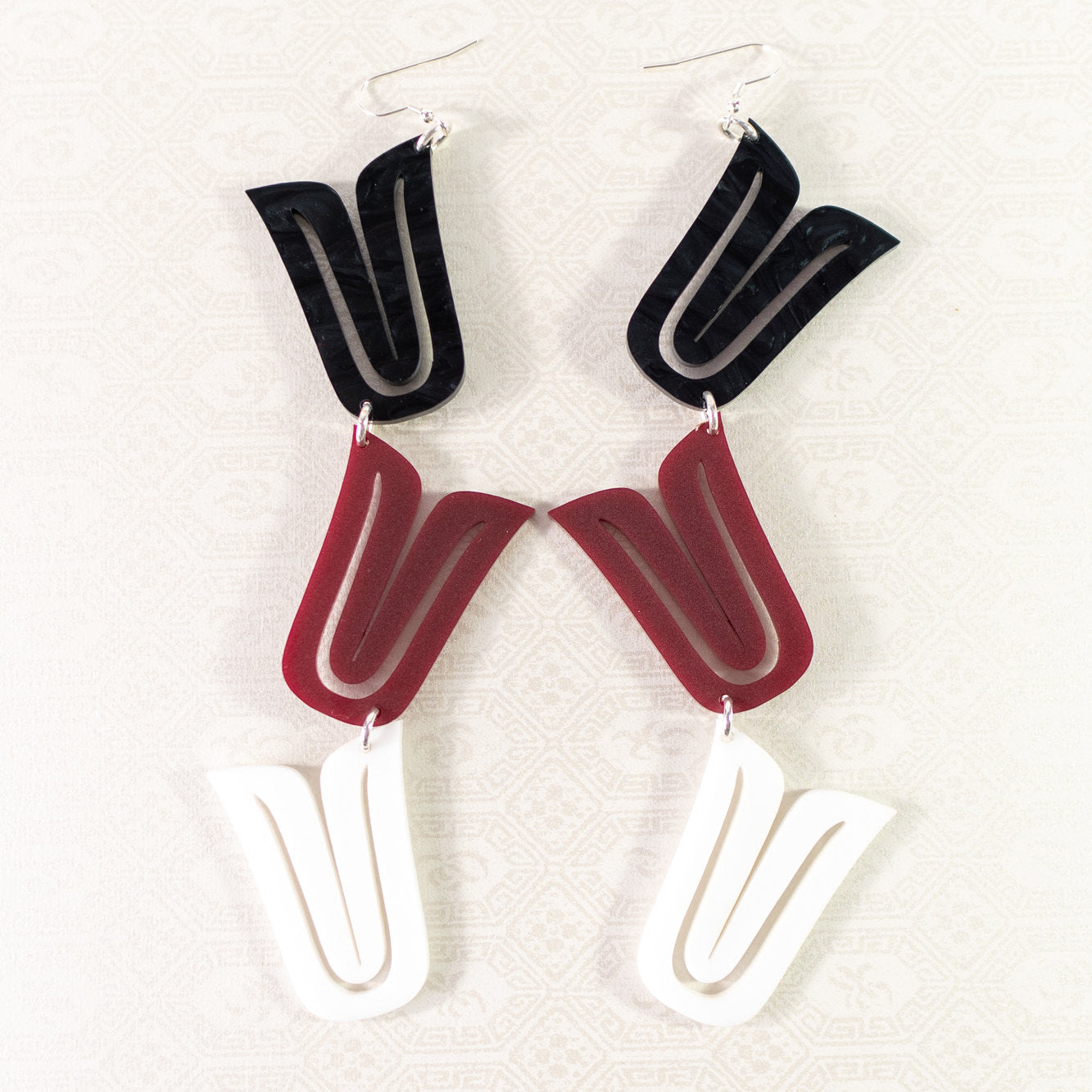 A pair of "Formline Cascade" earrings from Copper Canoe Woman laying on white fabric in the mixed colorway option.