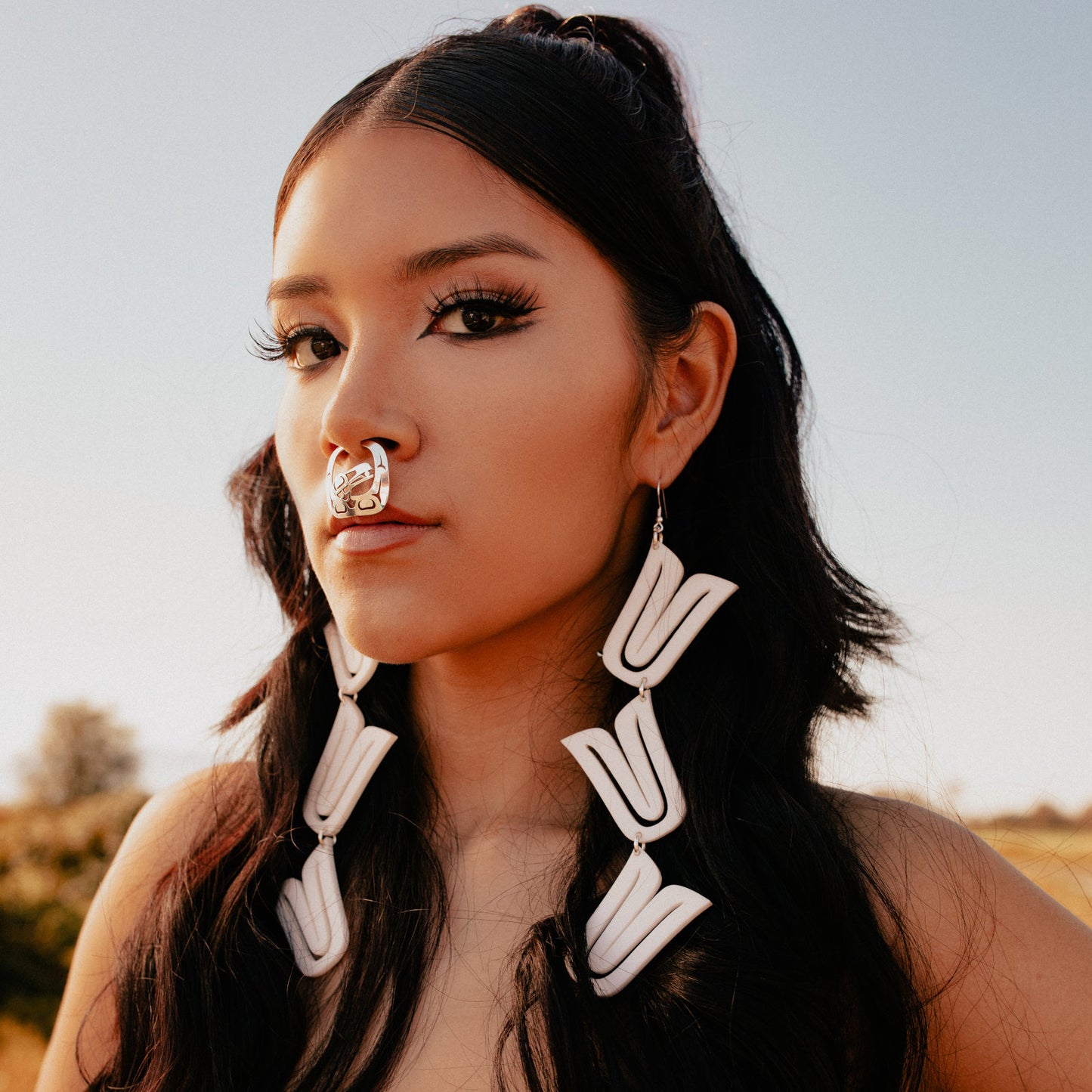 Model wearing white acrylic "Formline Cascade" earrings by Copper Canoe Woman.