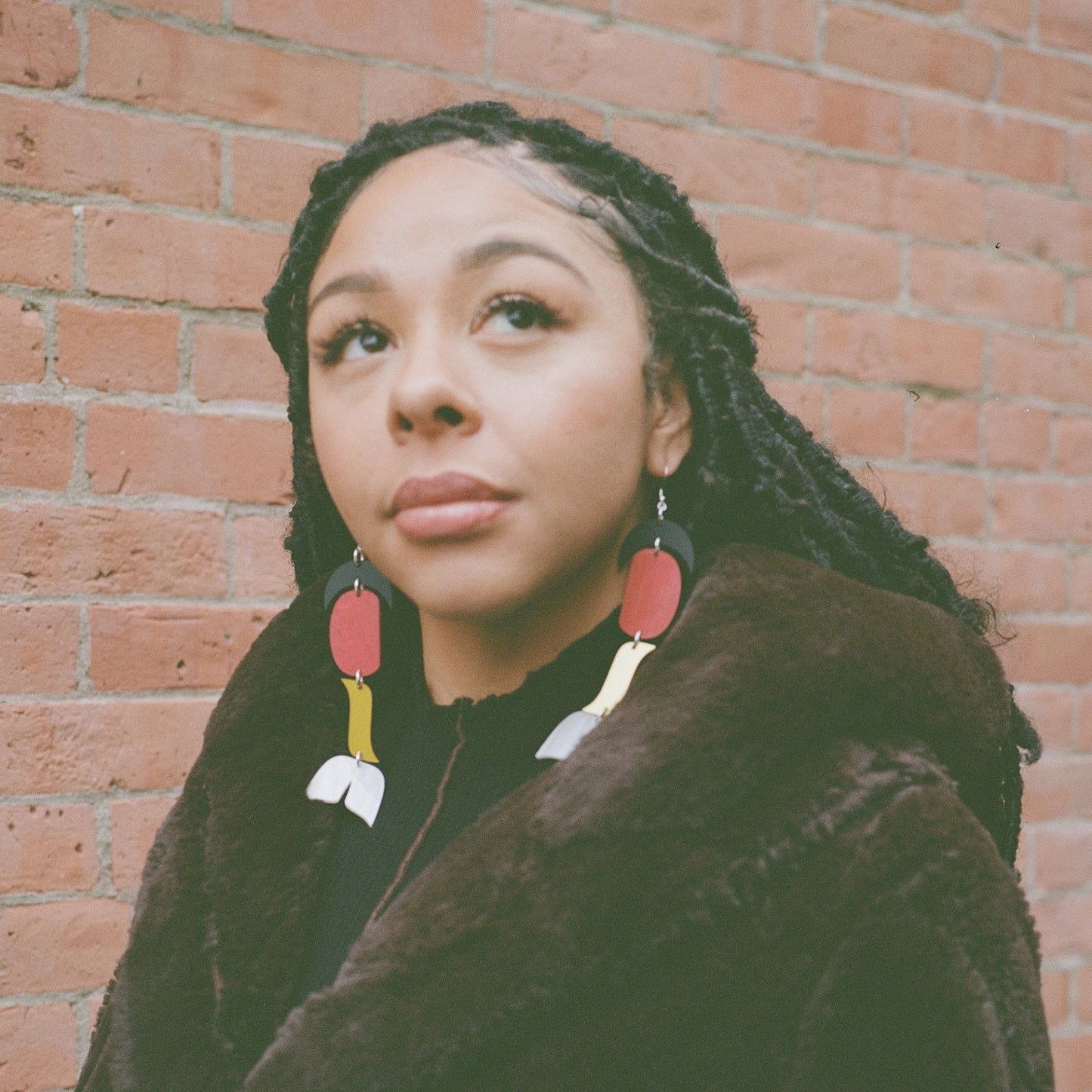 woman wearing abstract formline art earring in color sequence of black, red, yellow, white from copper canoe woman.