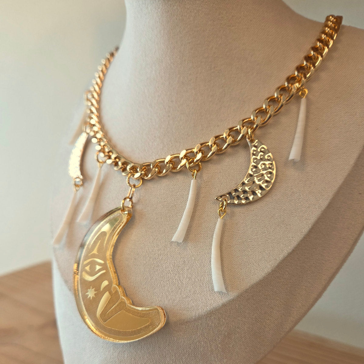 Angled view of a gold necklace with moon-shaped pendant and dentalium on a mannequin from Copper Canoe Woman.