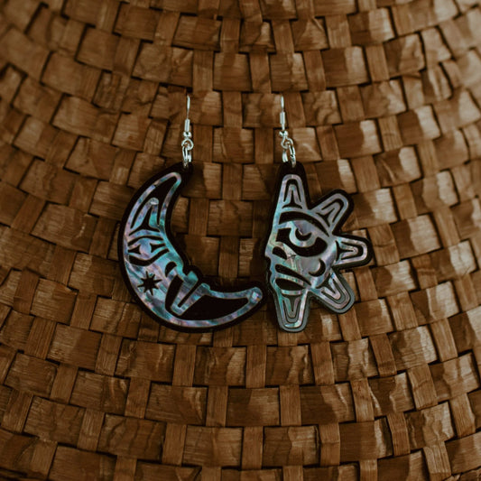 A pair of "Hupal" sun and moon earrings from Copper Canoe Woman hang from a cedar hat.