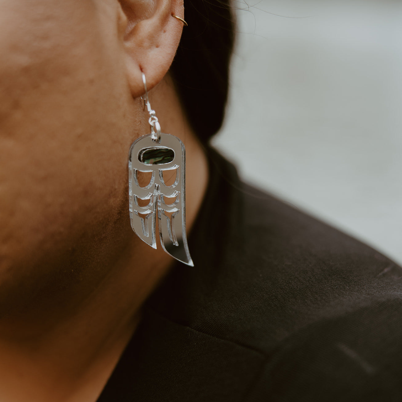 Closeup of a model wearing the silver mirror "Love Birds" earrings from Copper Canoe Woman.