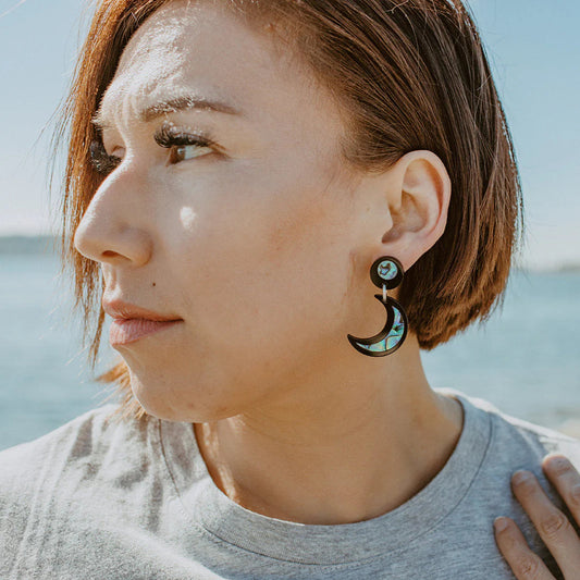 A model wearing black acrylic "Nuci" crescent moon earrings from Copper Canoe Woman.