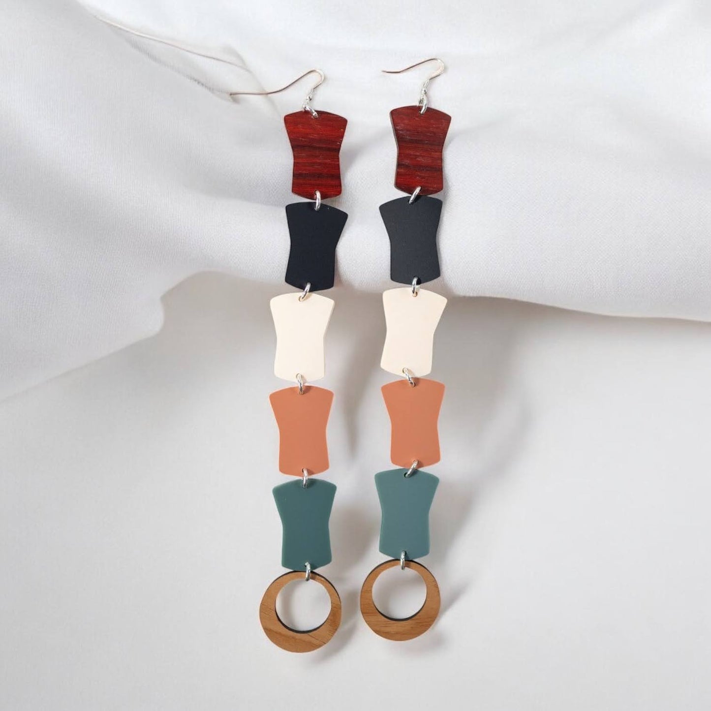 A pair of "Opulence Flow" earrings from Copper Canoe Woman laying on white fabric.