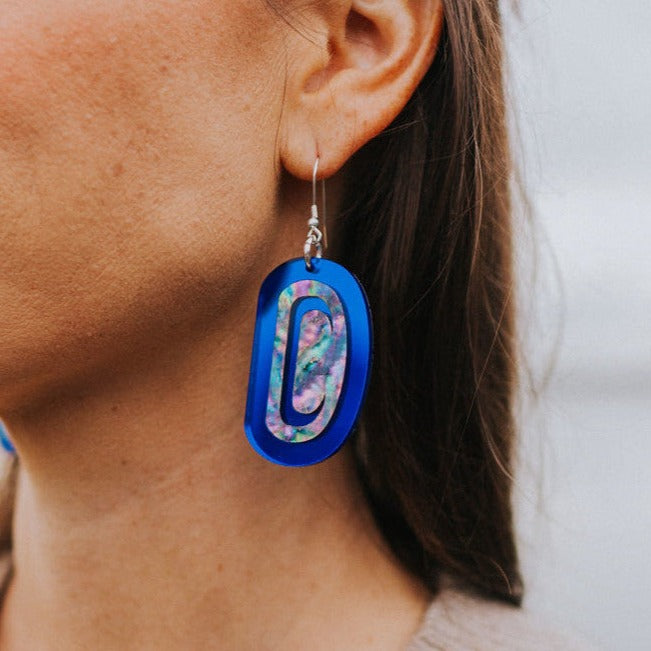 Closeup of a model wearing cobalt mirror "Abalone Ovoid" earrings from Copper Canoe Woman.