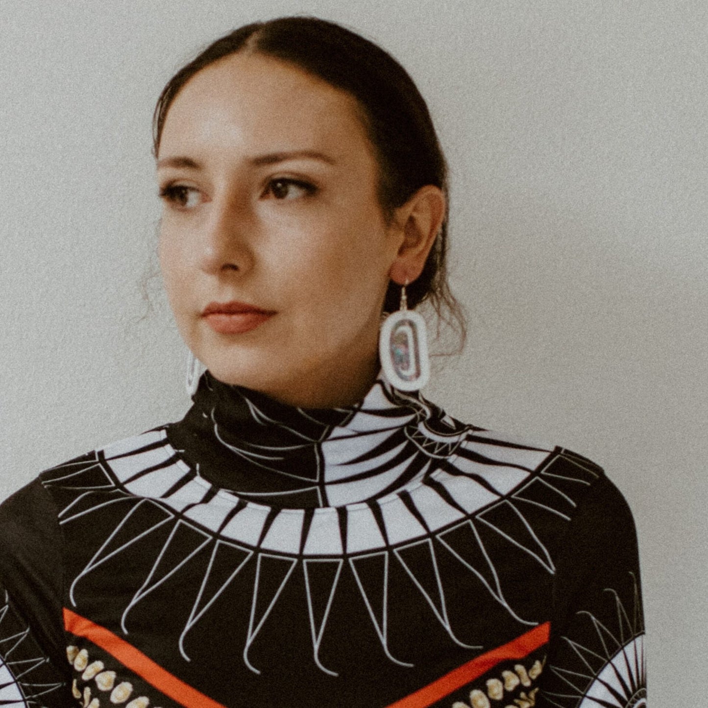 A model wearing white acrylic "Abalone Ovoid" earrings from Copper Canoe Woman.