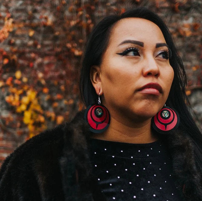"Owl Eye" earrings in crimson red acrylic from Copper Canoe Woman worn by a model.