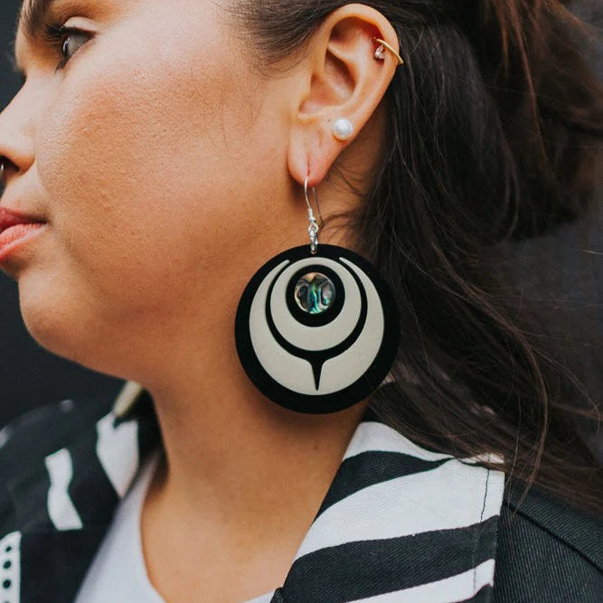 Closeup of a model wearing the ivory acrylic "Owl Eye" earring from Copper Canoe Woman.