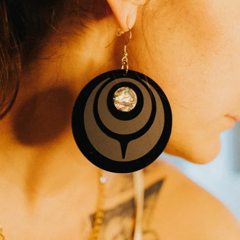 Closeup of the "Owl Eye" earring in jet black acrylic worn by a model from Copper Canoe Woman.