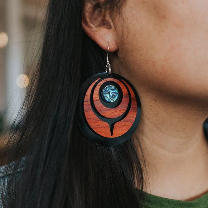 A closeup of a model wearing the padauk wood "Owl Eye" earring from Copper Canoe Woman.