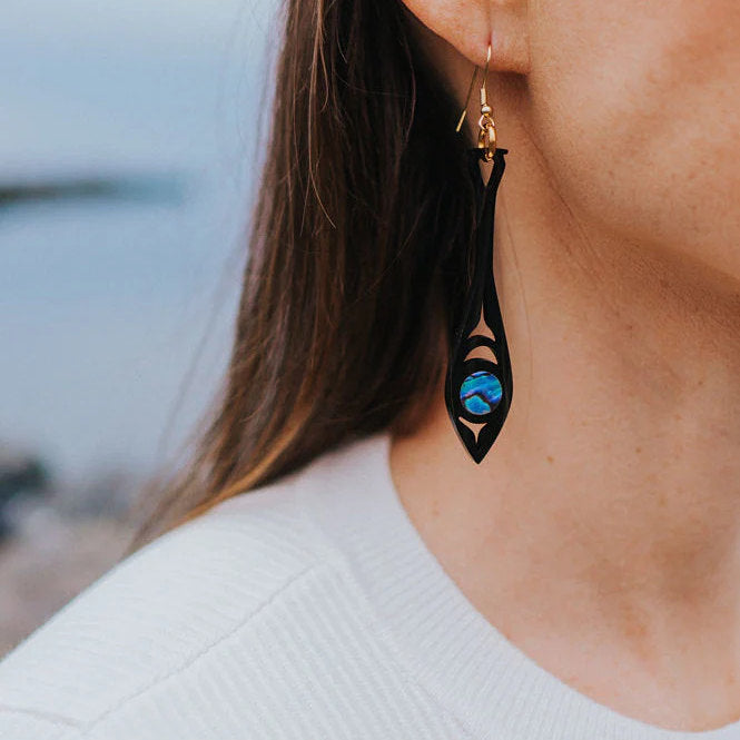 A closeup of a model wearing the black acrylic "Paddle Song" earring from Copper Canoe Woman.