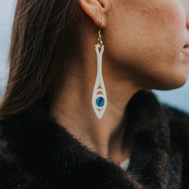 Ivory acrylic "Paddle Song" earring from Copper Canoe Woman worn by a model.