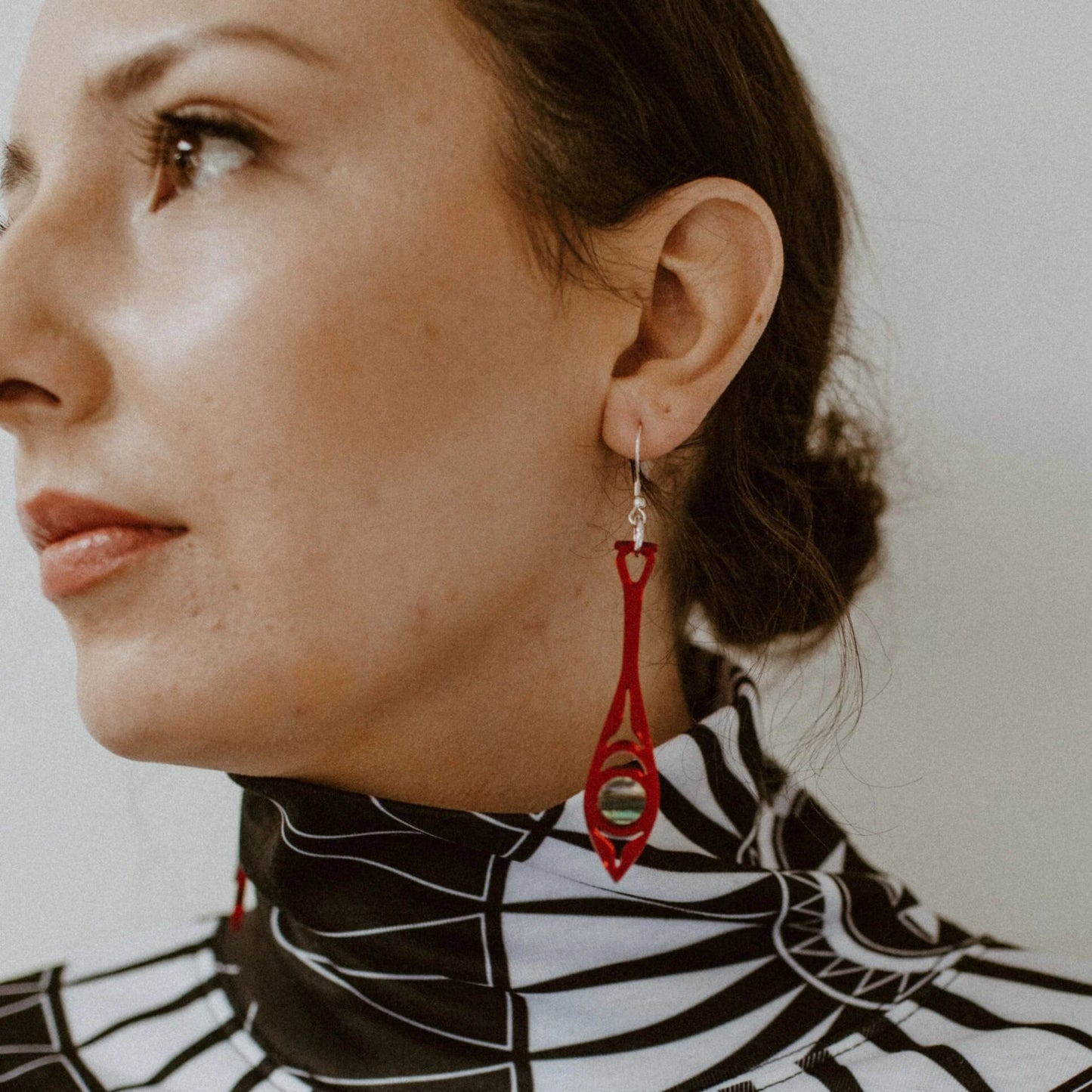 A model wearing red mirror acrylic "Paddle Song" earrings from Copper Canoe Woman.
