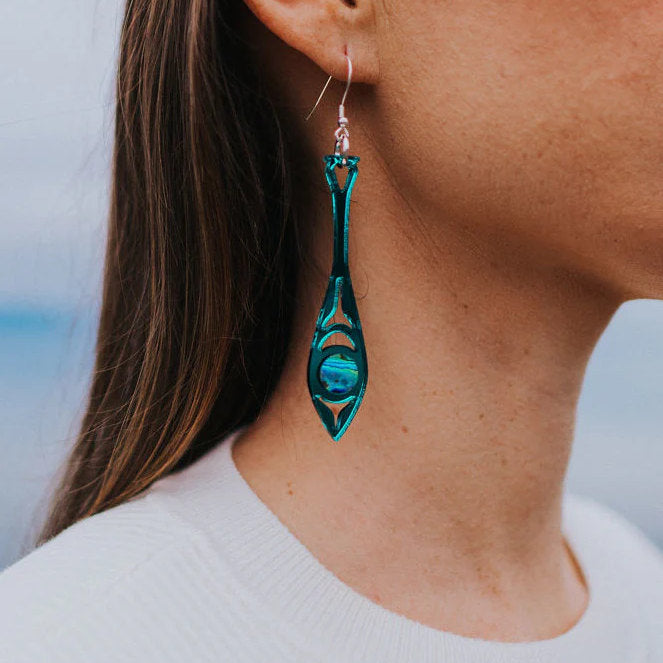 Closeup of the teal mirror acrylic "Paddle Song" earring from Copper Canoe Woman worn by a model.