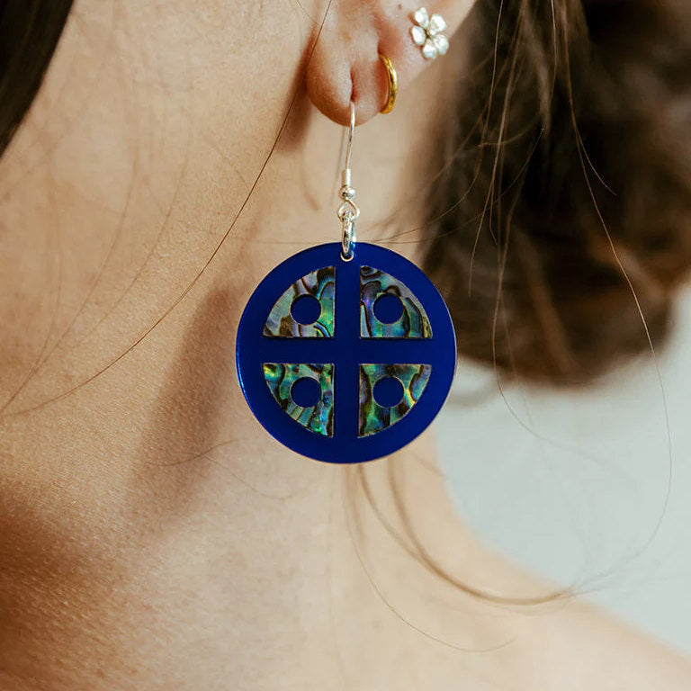 A close up of a model wearing the cobalt mirror acrylic "Protector Shield" earrings from Copper Canoe Woman.