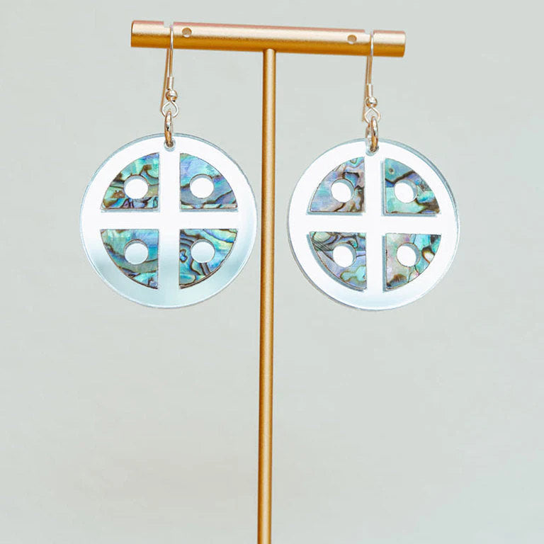"Protector Shield" earrings from Copper Canoe Woman in silver mirror acrylic hang from an earring display.