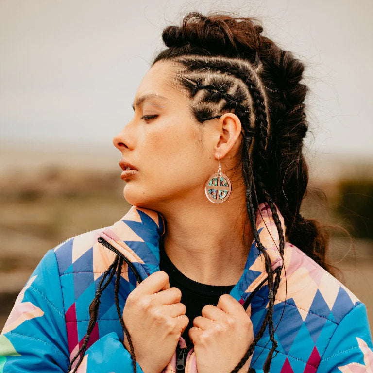 Profile of a model wearing Copper Canoe Woman "Protector Shield" earrings in rose gold mirror acrylic.