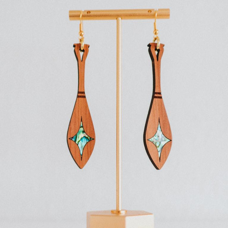 cedar paddle earring with star abalone inlay from copper canoe woman