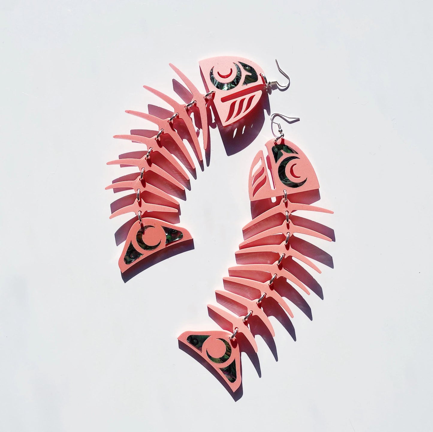 Matte coral acrylic large salmon ghost earrings from Copper Canoe Woman on a white background.