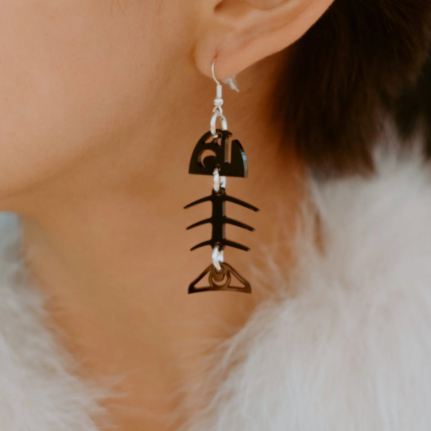 Closeup of Copper Canoe Woman black acrylic small salmon ghost earrings.