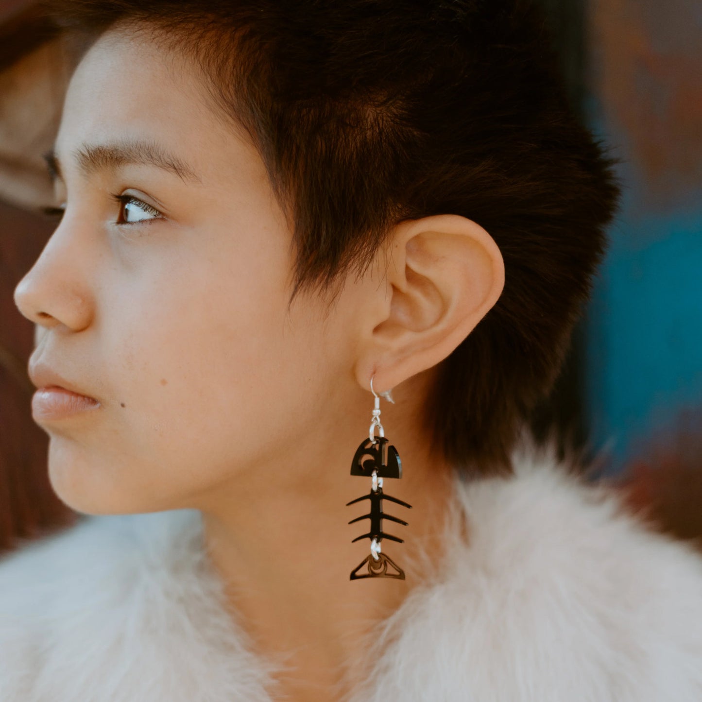 Profile of a model wearing the small salmon ghost earring in black acrylic from Copper Canoe Woman.