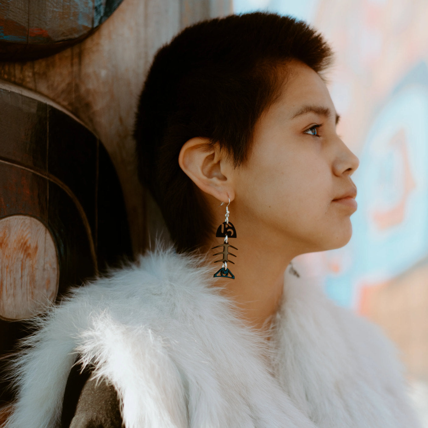 A youth model in profile wearing the black acrylic small salmon ghost earring from Copper Canoe Woman.