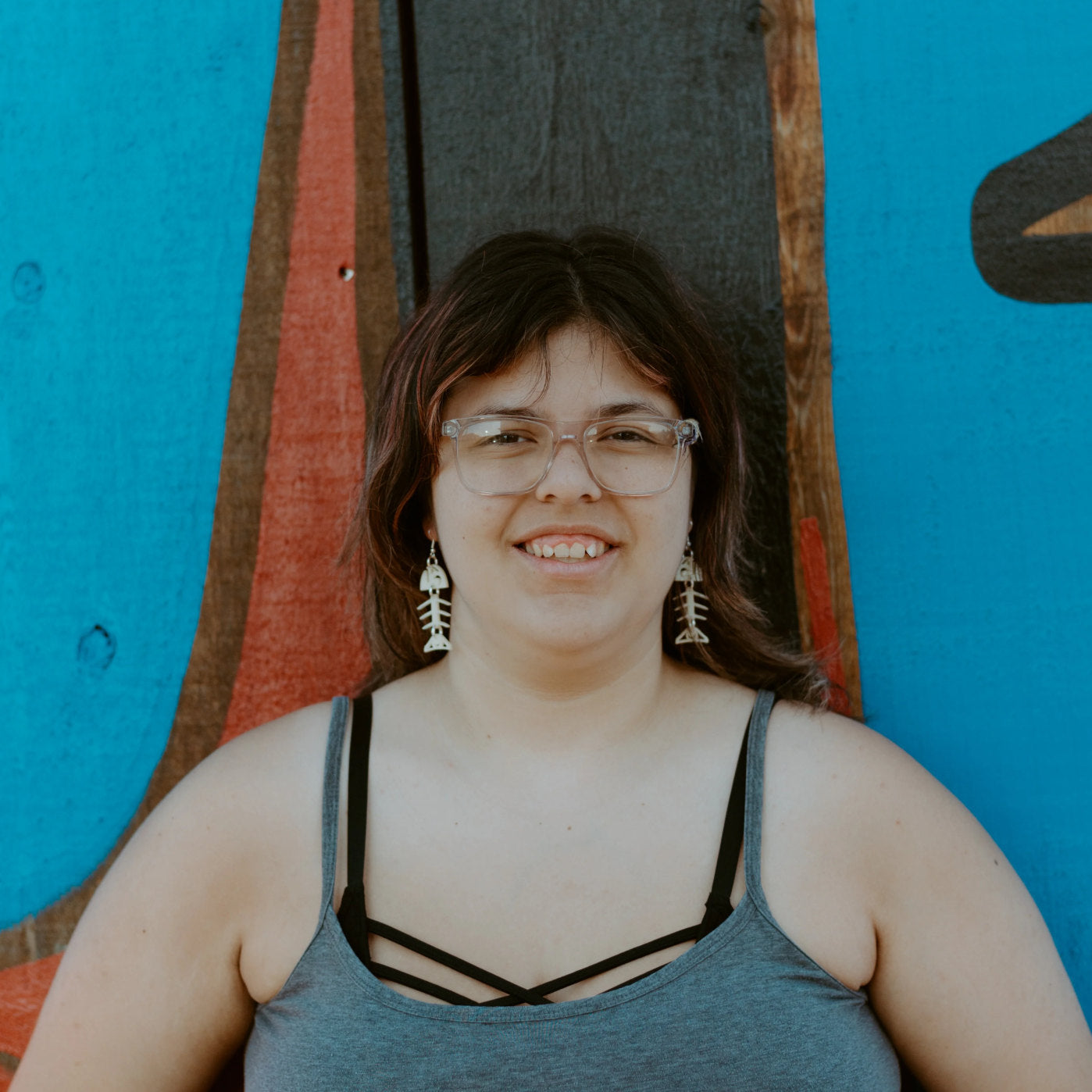 A model smiles at the camera while wearing the ivory acrylic small salmon ghost earrings from Copper Canoe Woman.
