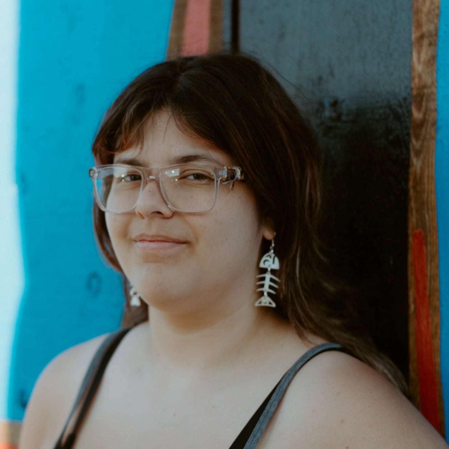 Copper Canoe Woman small salmon ghost earrings in ivory acrylic worn by a youth model who looks at the camera.