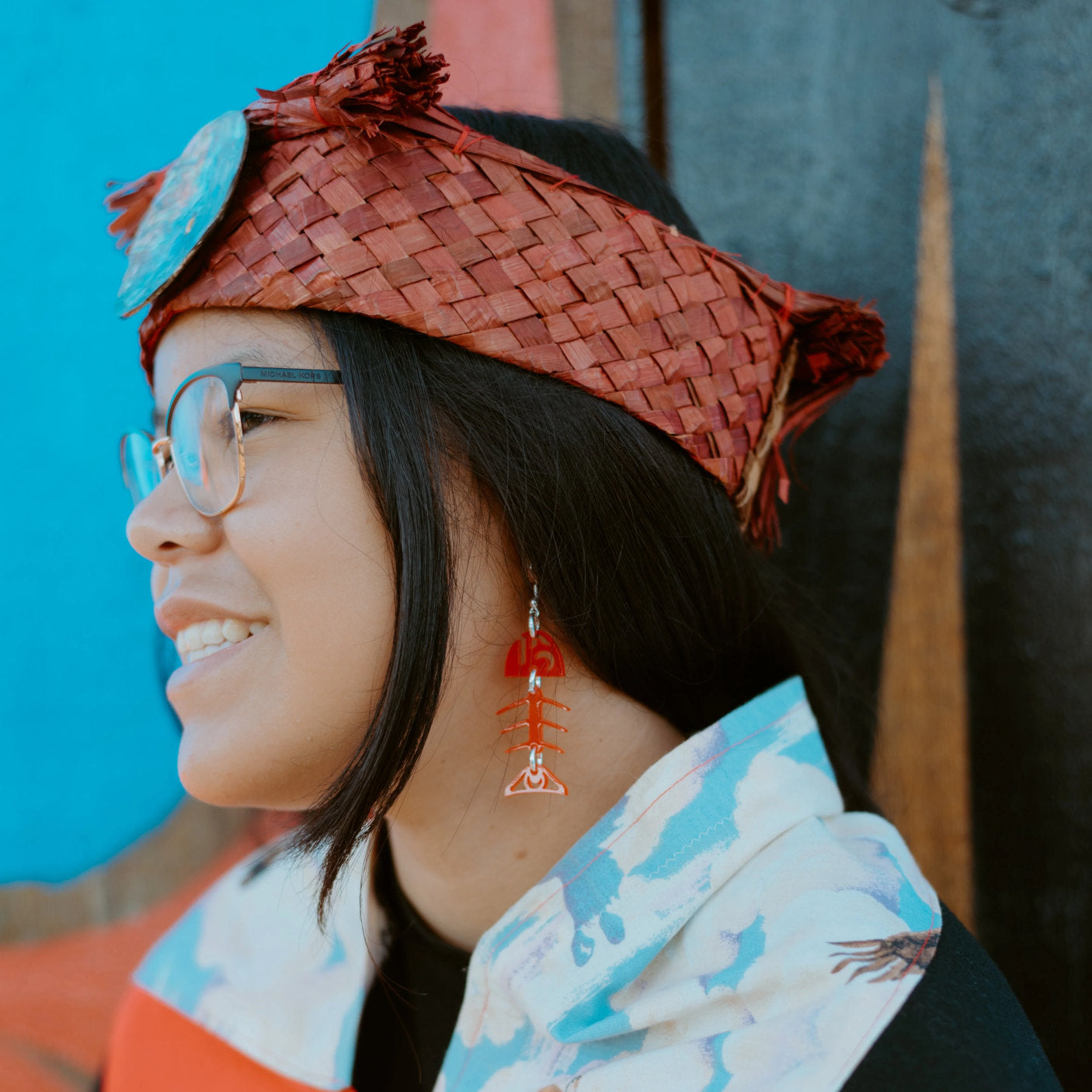Small salmon ghost earrings from Copper Canoe Woman in red acrylic worn by a youth in a cedar headband.