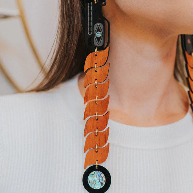 A closeup of a model wearing padauk wood serpent earrings from Copper Canoe Woman.