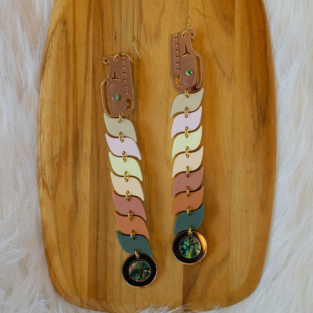 Serpent earrings laying on a wooden tray in pastel acrylic from Copper Canoe Woman.