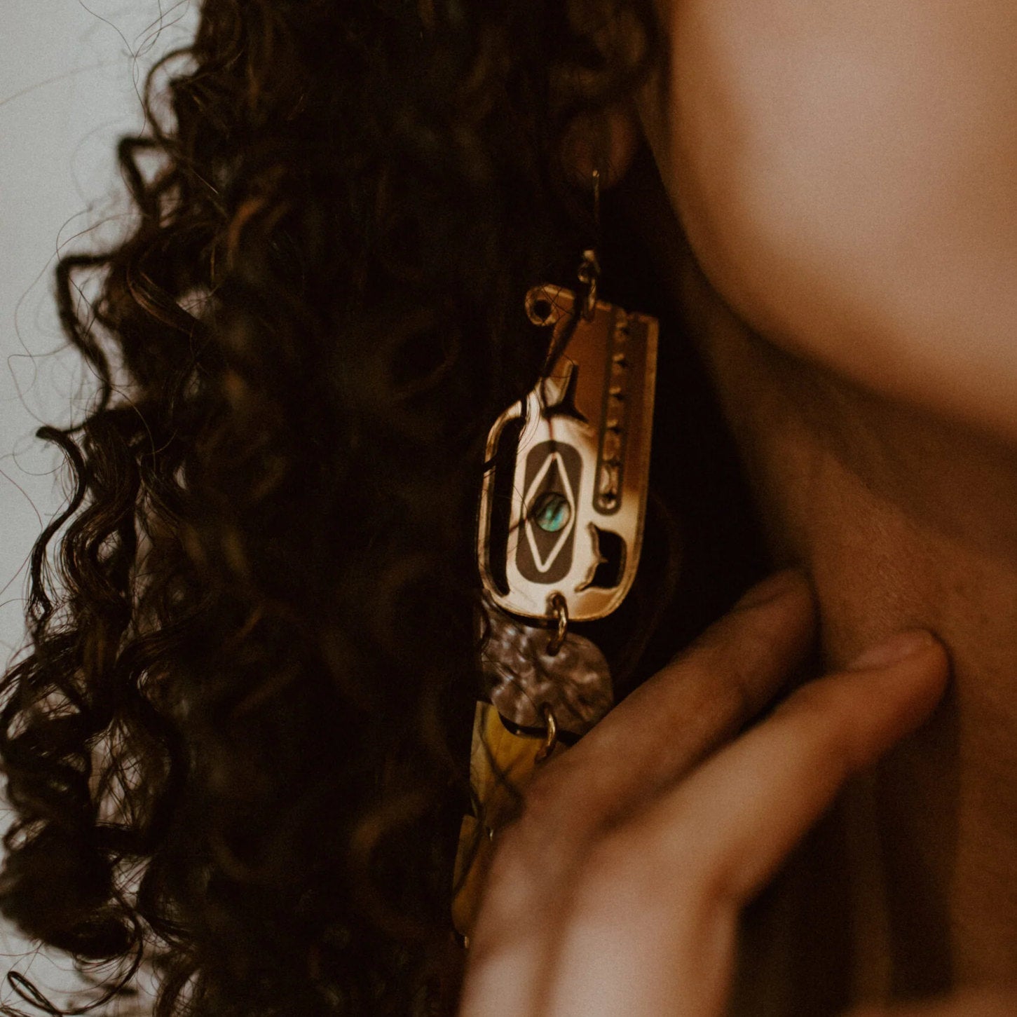 A closeup of the head of the Copper Canoe Woman serpent earring in gold mirror acrylic.