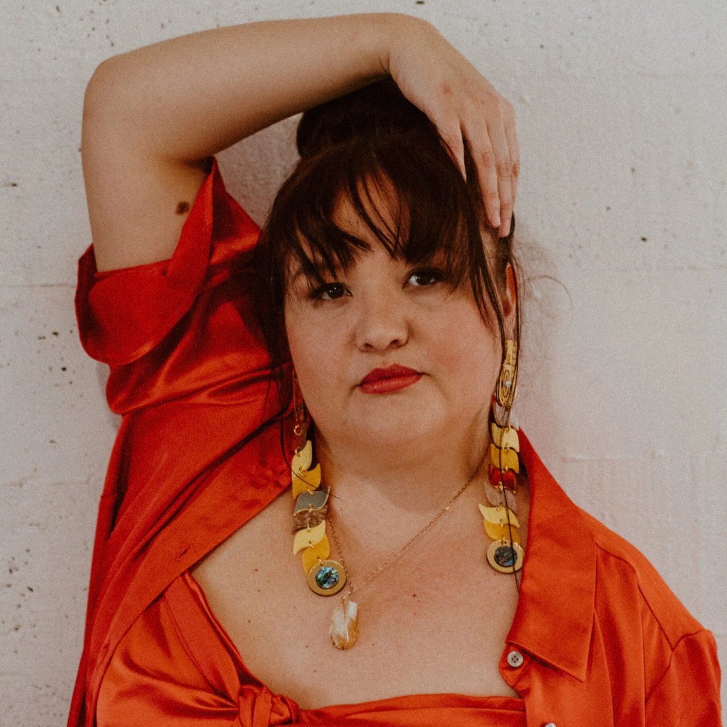 Copper Canoe woman yellow and gold mirror serpent earrings worn by a model.