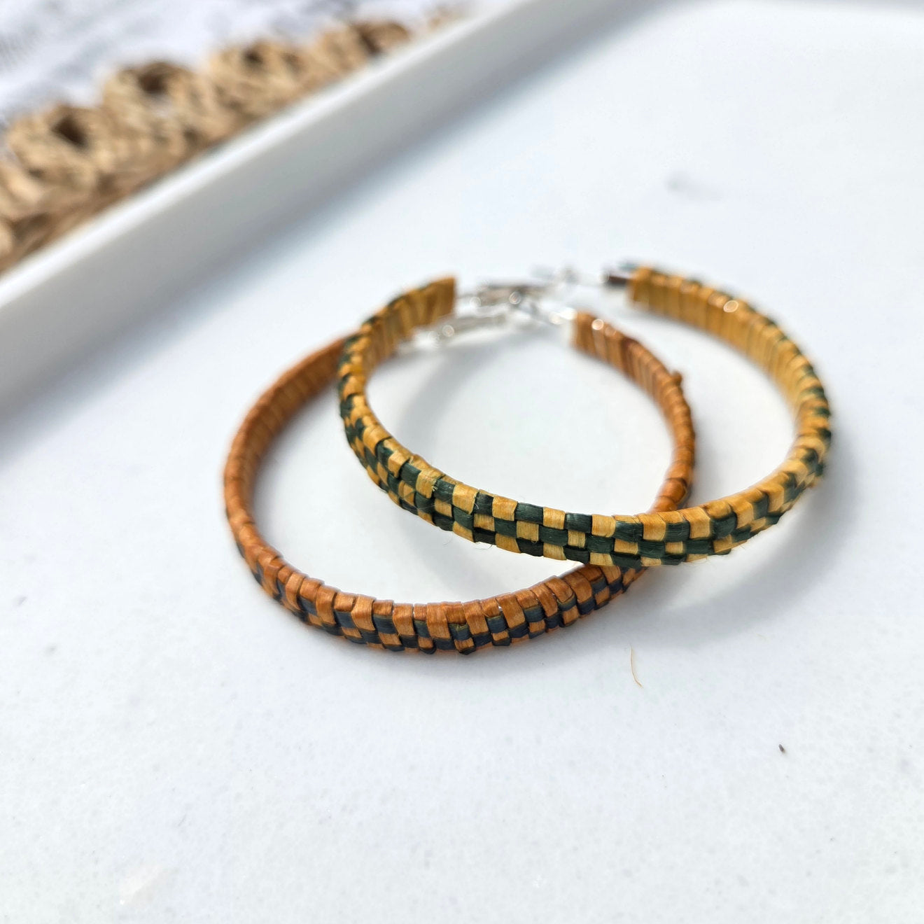 Two woven bracelets on a white surface with a natural fiber background.