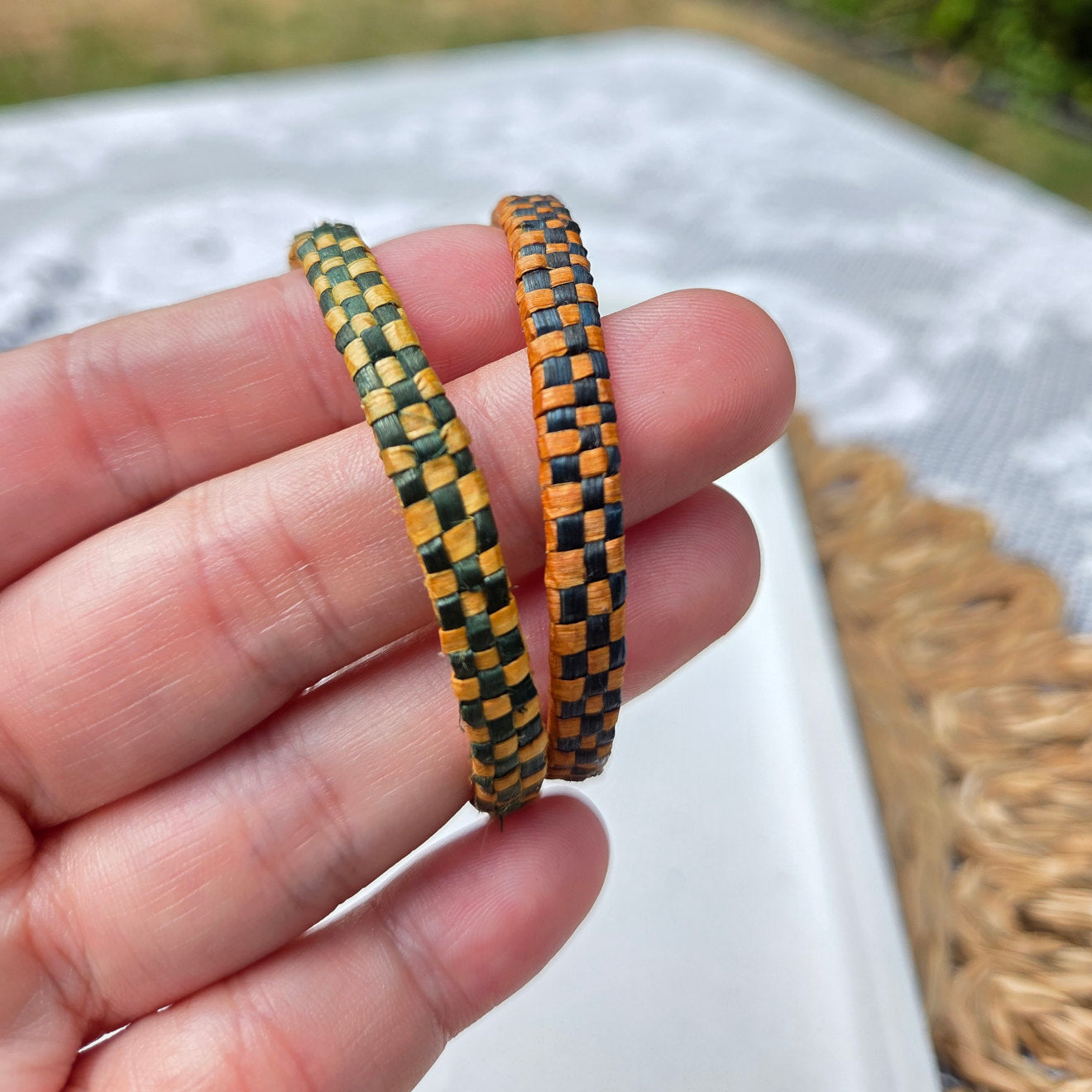 In Hand Pair of woven hoop earrings with red and black checkered pattern.