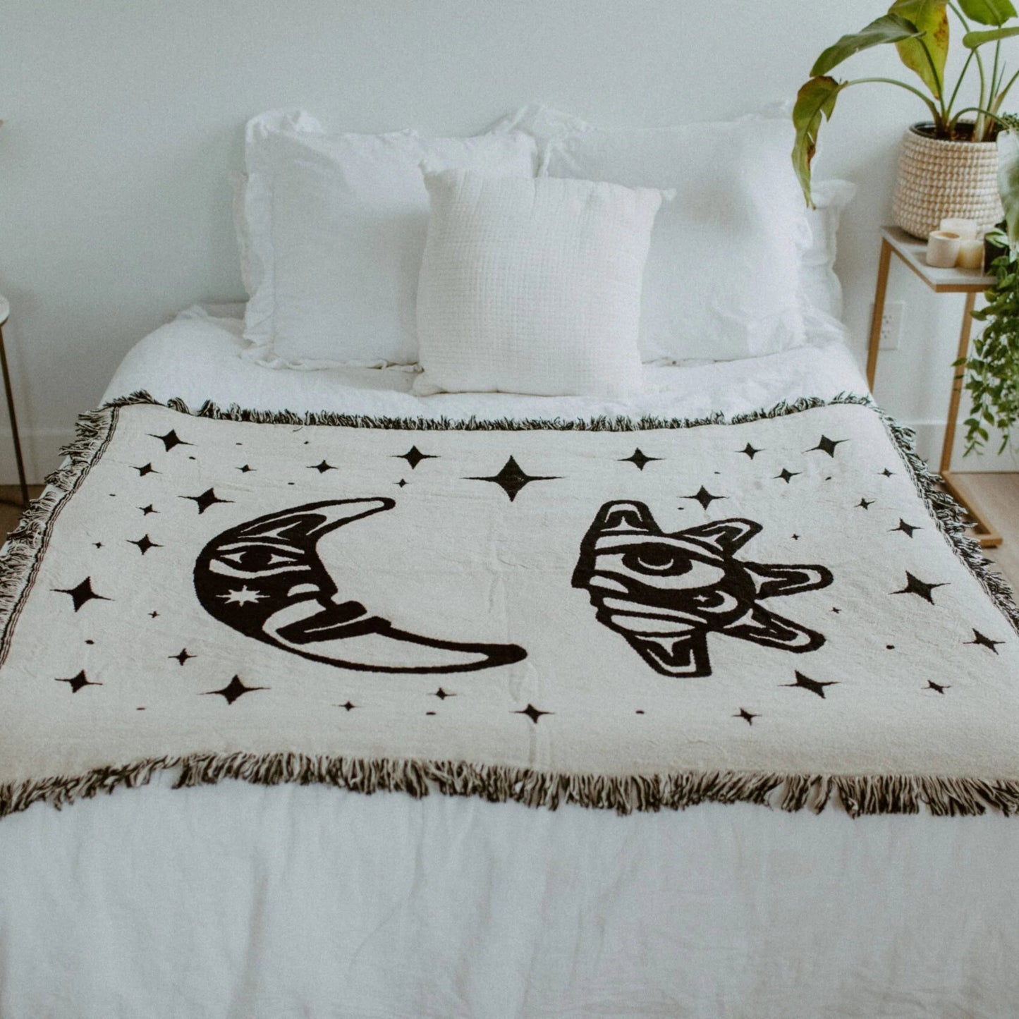 A "Hupal" sun and moon throw blanket from Copper Canoe Woman laying on a bed.