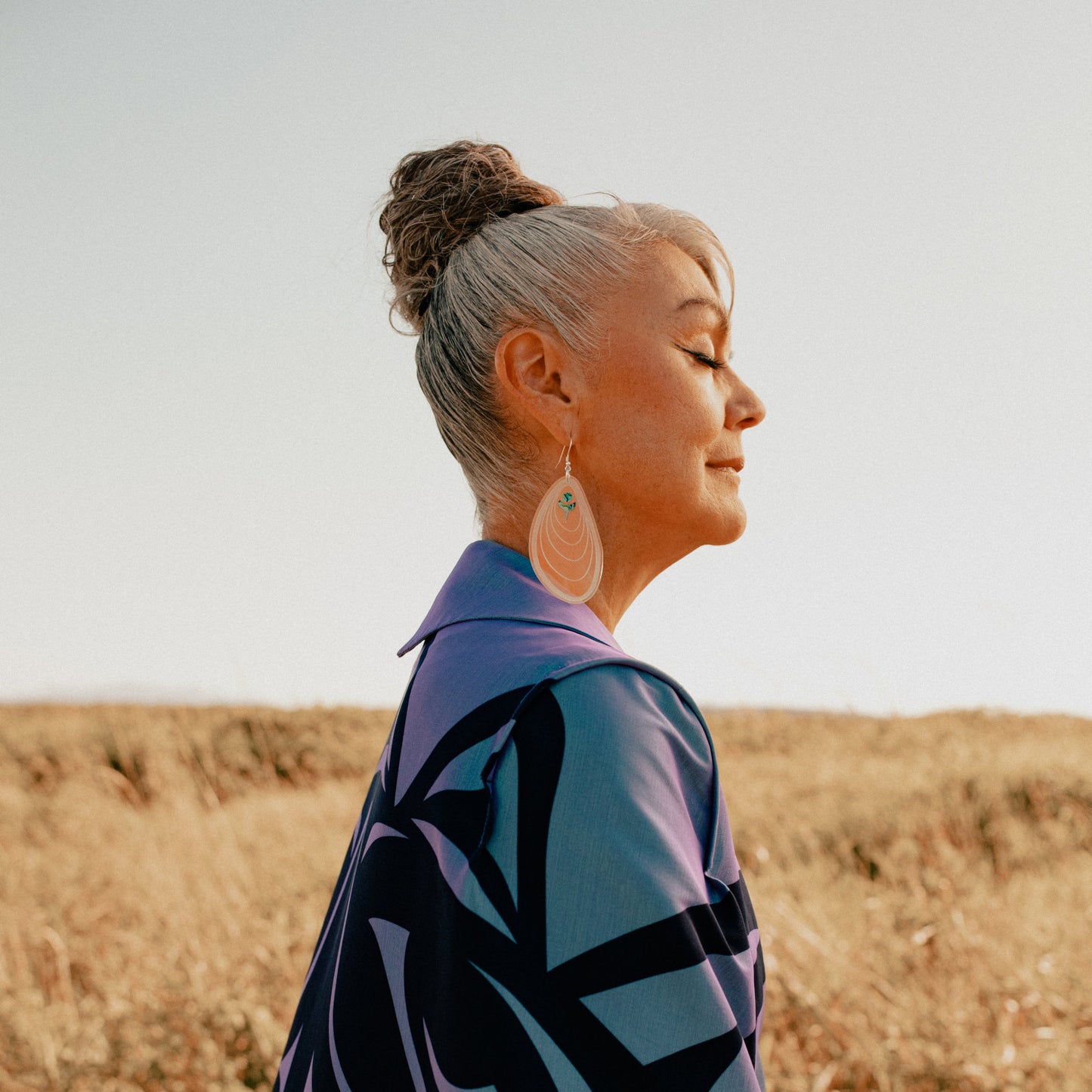 Profile of model wearing the "Tidal Ripples" earring in iridescent acrylic from Copper Canoe Woman.