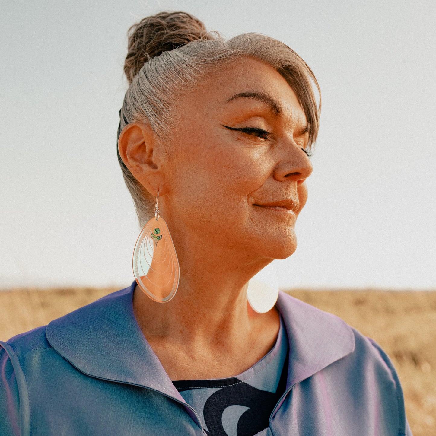 A model wearing the mussel-inspired "Tidal Ripples" earring in iridescent acrylic from Copper Canoe Woman.