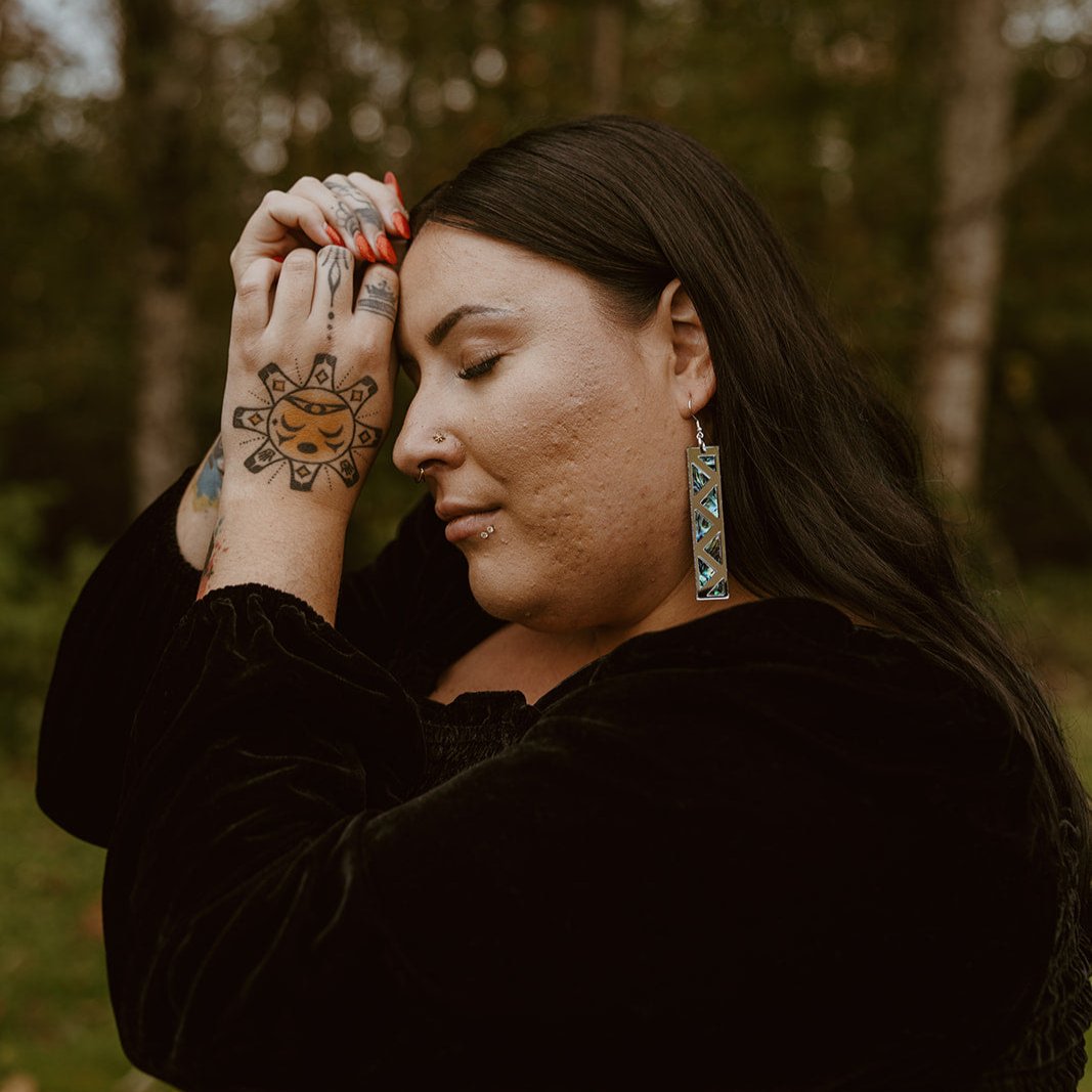 woman wearing silver mirror long rectangle warrior spirit earring with triangle zig zag abalone inlay from copper canoe woman