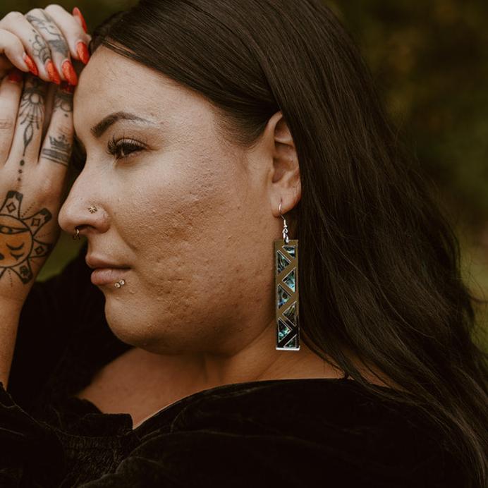close up woman wearing silver mirror long rectangle warrior spirit earring with triangle zig zag abalone inlay from copper canoe woman