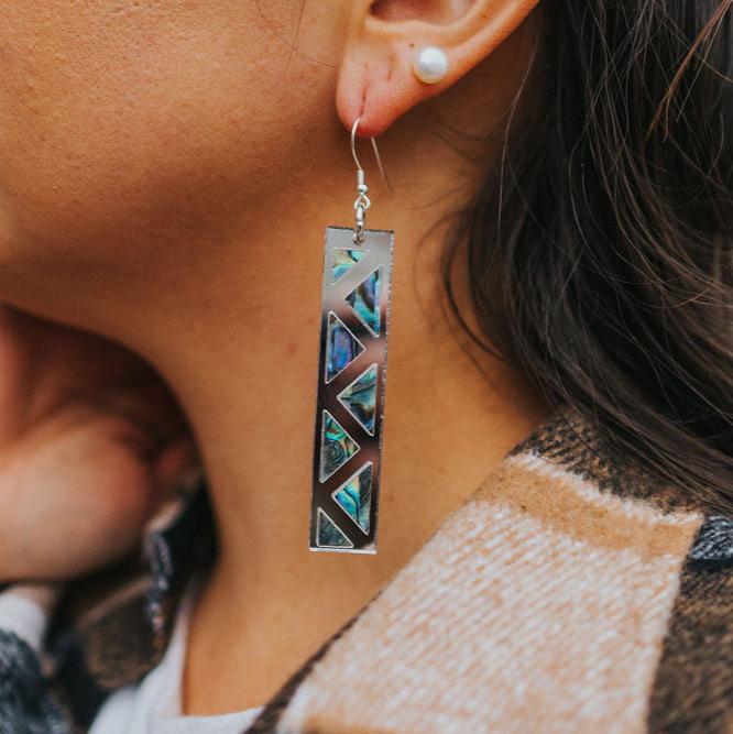 close up of woman wearing silver mirror long rectangle warrior spirit earring with triangle zig zag abalone inlay from copper canoe woman