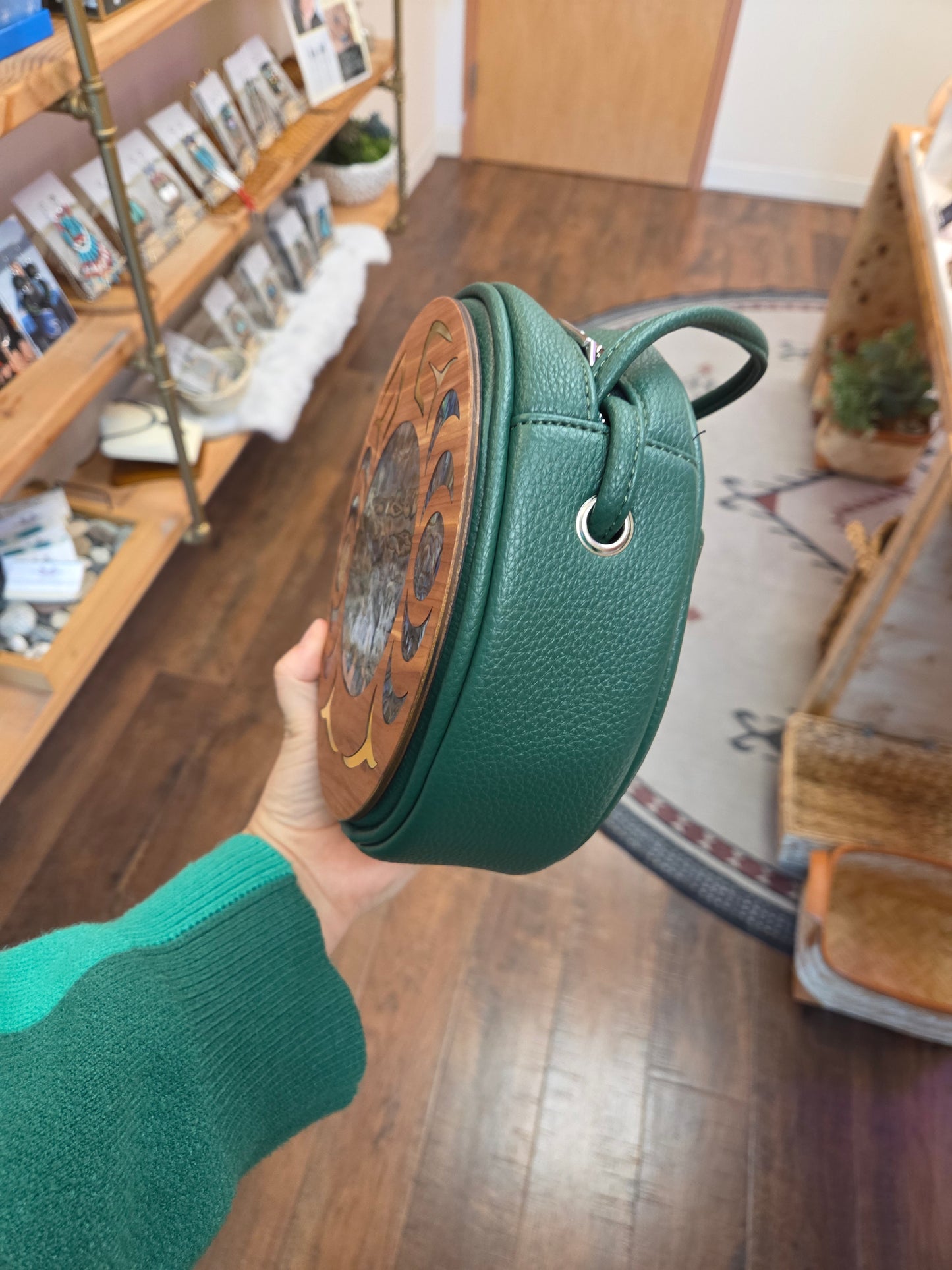 Green round bag held by a person in a store setting