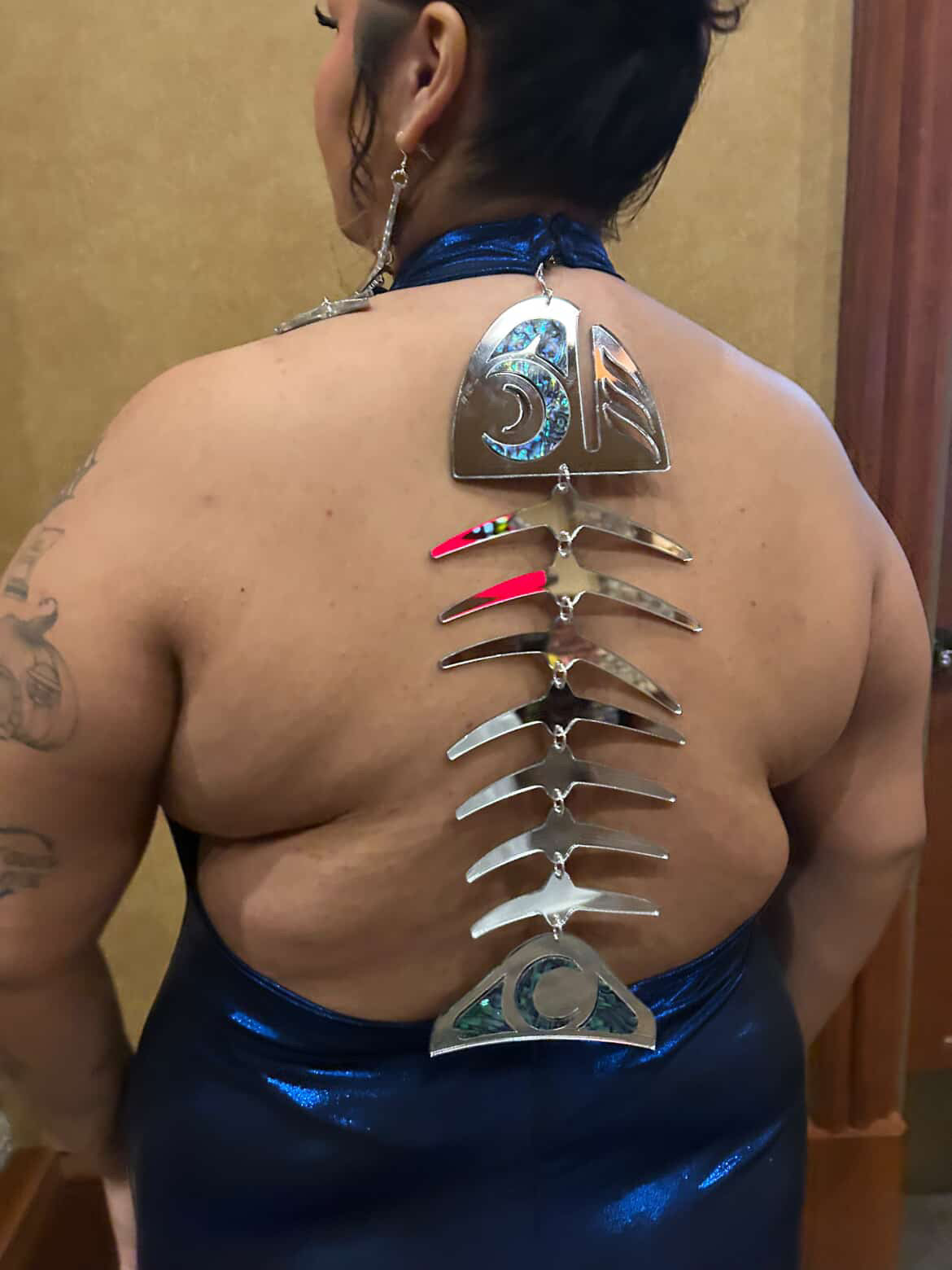 Person wearing a blue dress with decorative back piece