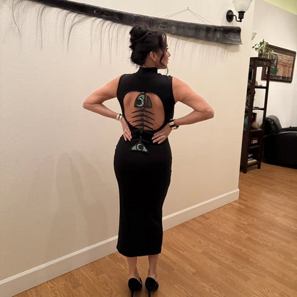 Woman wearing a black dress with an open back design in a room.