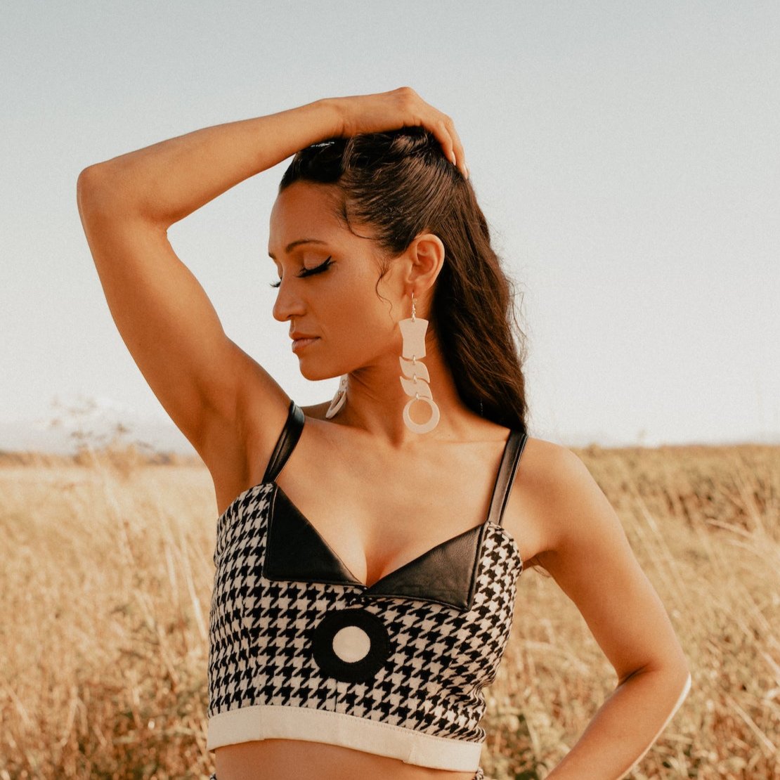 Woman wearing abstract formline art in ivory color. Top is copper shield, followed by two s shaped formline shapes, and the bottom a circle. earrings from copper canoe woman