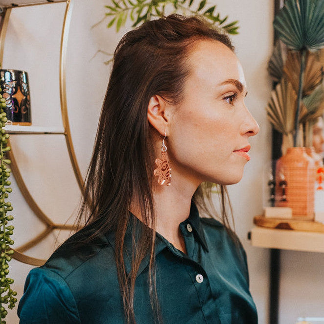 A model wearing the "Balance Sun" earring from Copper Canoe Woman in rose gold mirror acrylic.